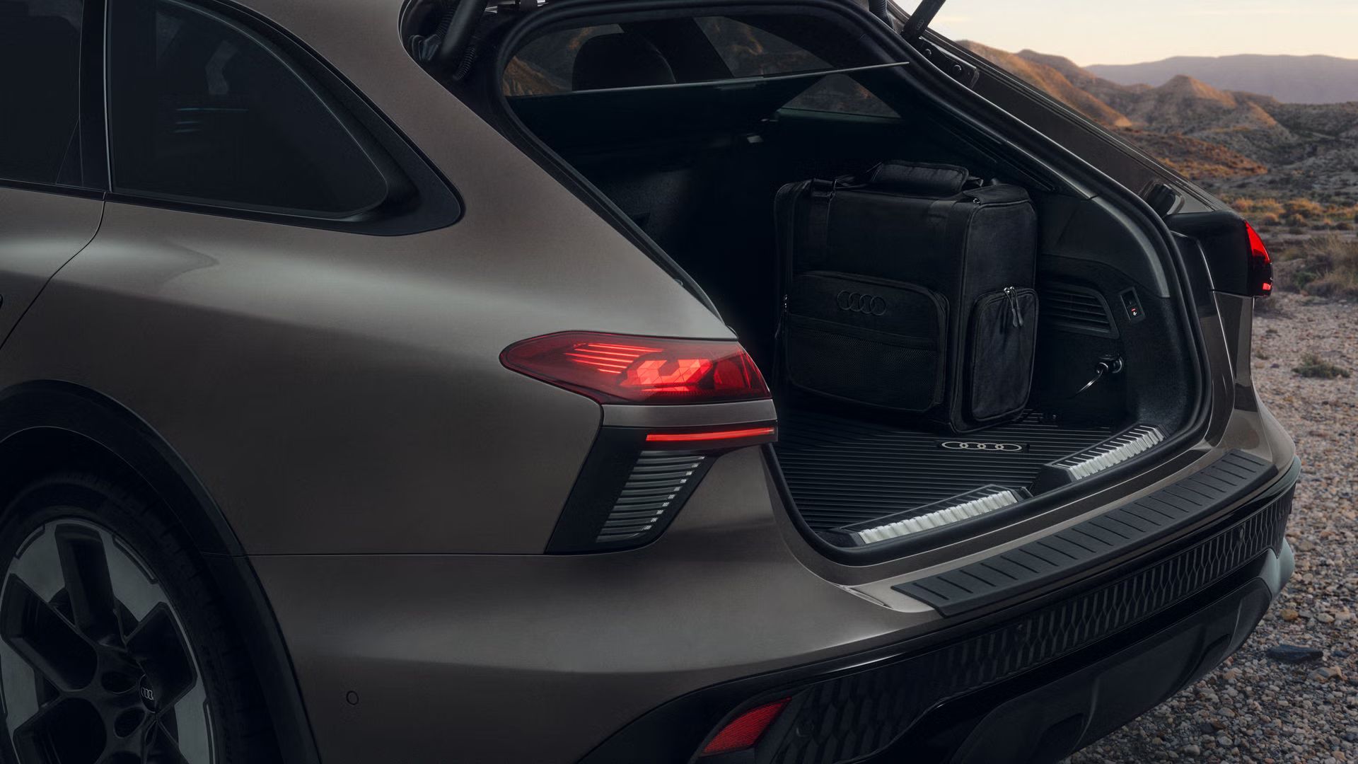 Nahaufnahme des Hecks eines Audi A6 allroads, der auf einer Schotterstraße parkt. Im geöffnetem Kofferraum steht die 14-Liter-Kühlbox.