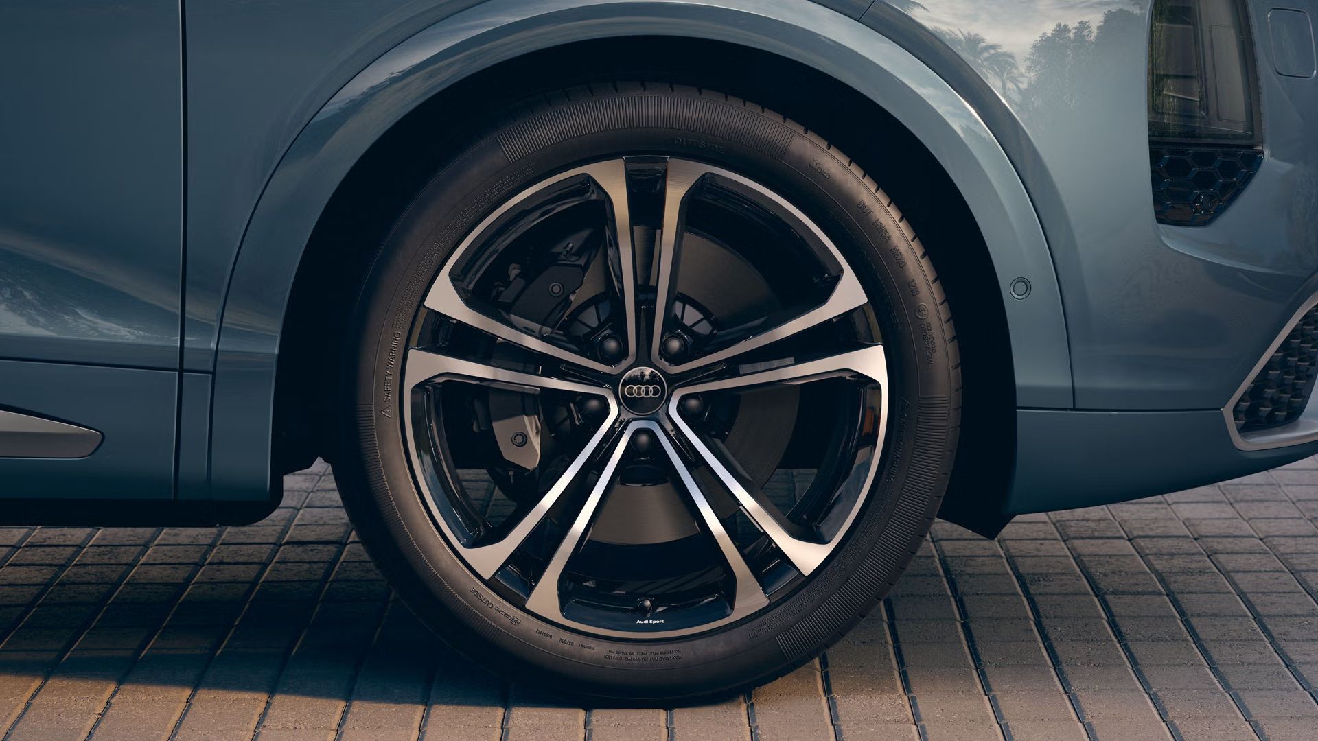 Nahaufnahme eines Audi-Rads mit 22 Zoll Audi Sport Leichtmetallfelgen im Vielspeichen-S-Design in Schwarz Metallic.